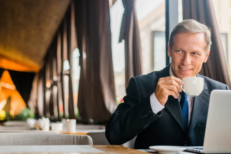 happy-businessman-drinking-coffee-with-laptop-desk