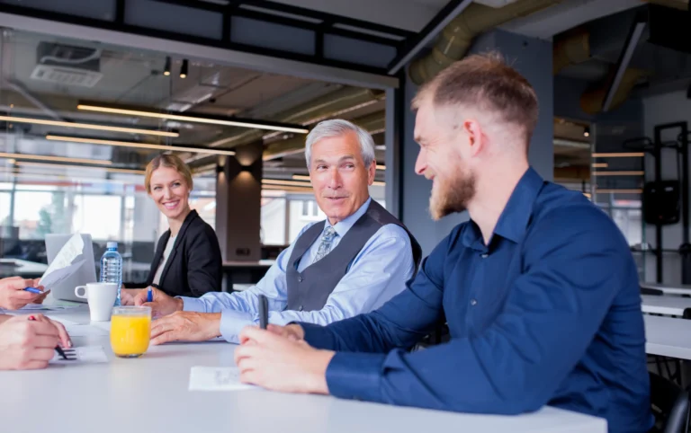 smiling-senior-manager-with-his-employees-sitting-together-meeting